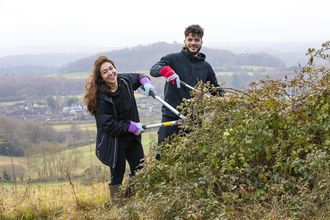 Young people using tools to manage a hedge 